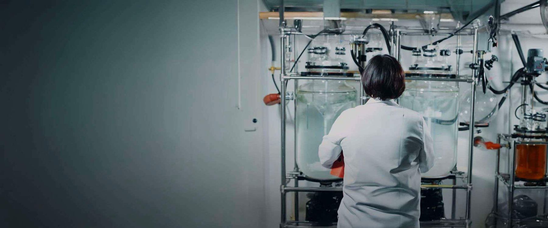 A chemist working at glass reactors in a process development lab