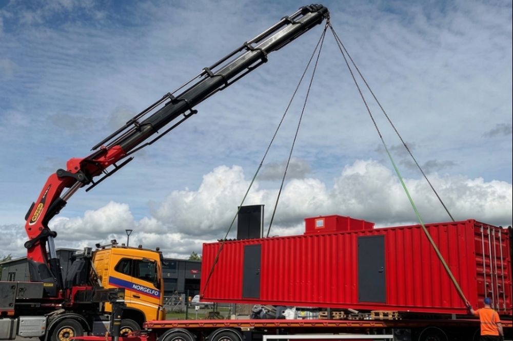 A containerised processing unit being craned onto a flatbed trailer