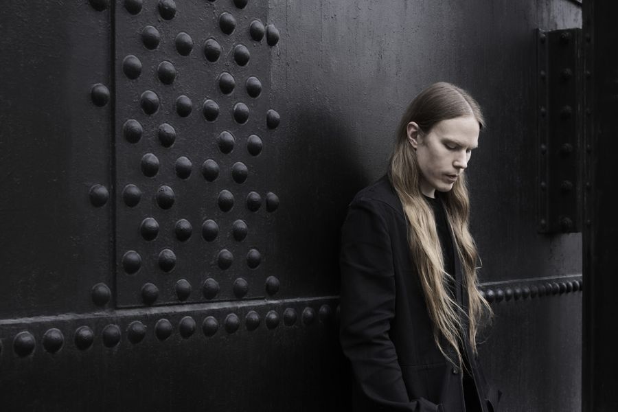 Fashion designer Sami Eskelinen against a riveted steel wall