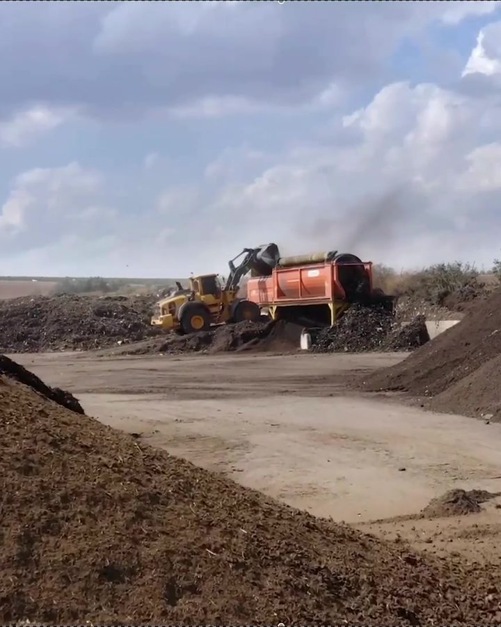 Side-stream heaps at a processing site, with a loader at work